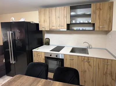 a kitchen with wooden cabinets and a black refrigerator at Кольовата къща Тетевен in Teteven