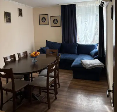 a living room with a table and a blue couch at Кольовата къща Тетевен in Teteven