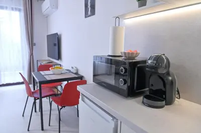 a kitchen with a microwave and a table with red chairs at White Peaks 1BR Apartment Bansko by SI Stay in Bansko