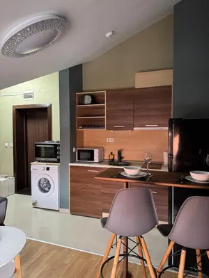 a kitchen with wooden cabinets and a counter with chairs at Belmont Apartment in Bansko