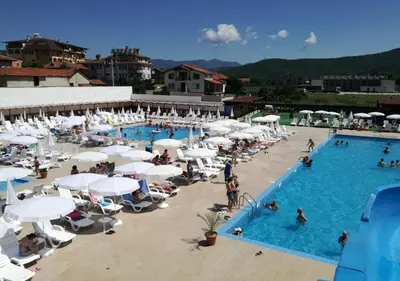 a large pool with white umbrellas and people in it at Апартамент Боров рай in Velingrad