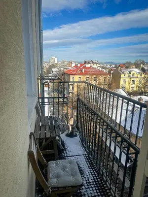 a cat sitting on a balcony looking out of a window at Serdika Central Stay - 2BD next to Serdika Metro Station in Sofia