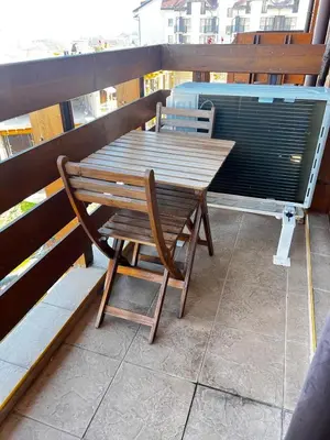 a wooden table and a chair sitting on a balcony at BANSKO Deluxe Apartment Belvedere - 350m SkiLift in Bansko