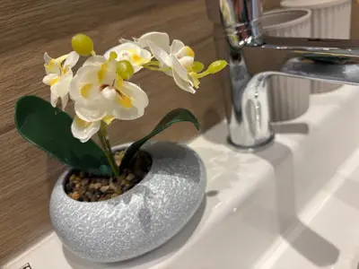 a vase with white flowers sitting on a bathroom sink at Luxury & Comfort near the University in Blagoevgrad