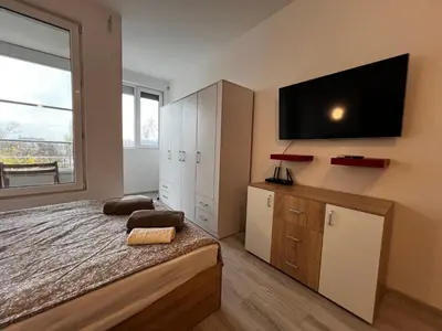 a bedroom with a bed and a tv on the wall at Warsaw Cozy Studio near UNSS and NSA with Balcony in Sofia