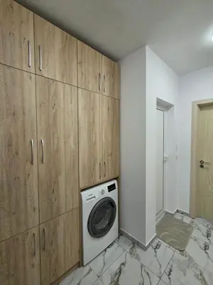 a laundry room with a washing machine and wooden cabinets at Apartment Lily Complex Padaloto in Smolyan