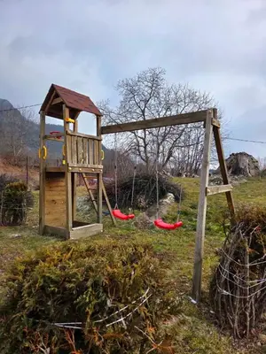 a wooden playground with two swings in a field at Apartment Lily Complex Padaloto in Smolyan