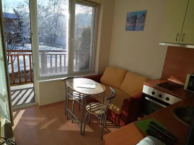 a living room with a couch and a table and a kitchen at Sunny Studio Eagle Rock in Beli Iskar