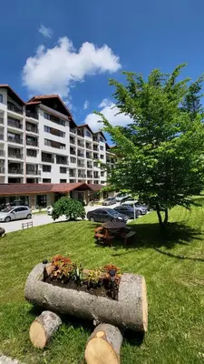 a planter in the grass in front of a building at Private studio B27 in Borovets Gardens in Borovets