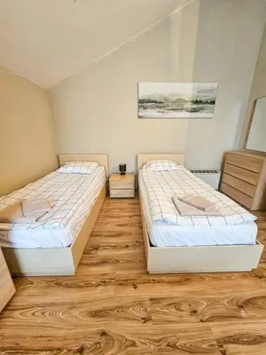 two beds in a room with wooden floors at Vista Apartment in Borovets