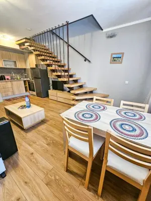 a room with a table and chairs and stairs at Vista Apartment in Borovets