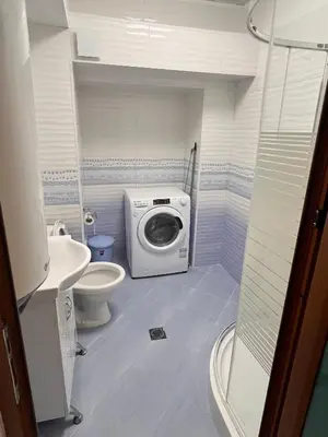 a bathroom with a washing machine and a toilet at Апартамент Аксел in Panagyurishte