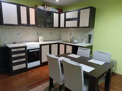a kitchen with a table and white chairs in it at Марковата Къща in Madzhare