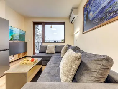 a living room with a large couch and a tv at Alpine Glow Studio with Parking Pamporovo in Pamporovo