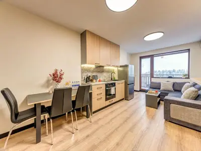 a kitchen and living room with a table and a couch at Alpine Glow Studio with Parking Pamporovo in Pamporovo