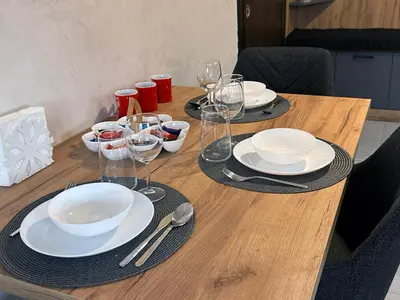 a wooden table with plates and wine glasses on it at New! Park Lane Bansko Residences in Bansko