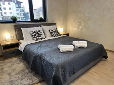 a bedroom with a large bed with two towels on it at New! Park Lane Bansko Residences in Bansko