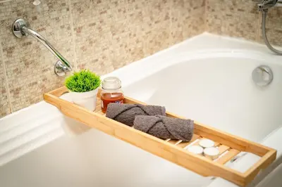 a bathtub with a wooden tray with towels and a plant at Bansko Peak Apartments 102 in Bansko