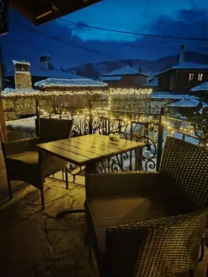 a table and chairs on a balcony with lights at Guest House Zlatniyat Telets in Koprivshtitsa