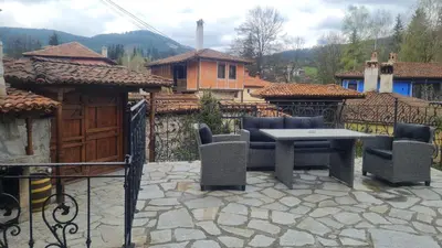 a patio with a table and chairs and a fence at Guest House Zlatniyat Telets in Koprivshtitsa