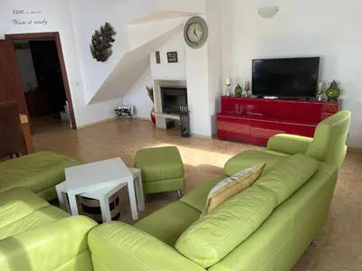 a living room with a green couch and a tv at Villa Dreams in Golf Club Ibar in Dolna Banya
