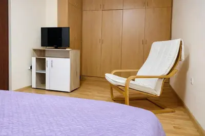 a room with a bed and a chair and a tv at Prime Apartment Seven & Parking in Plovdiv