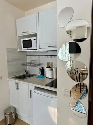 a white kitchen with white cabinets and a microwave at Panorama Studio Home2Host in Bansko