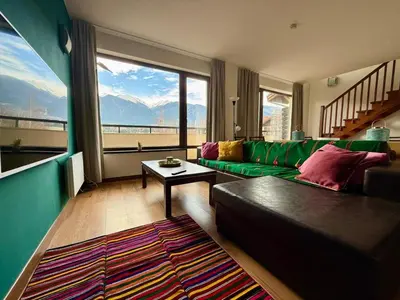 a living room with a green couch and a large window at Golf view in Razlog