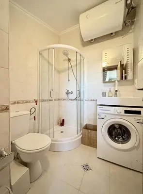 a bathroom with a shower toilet and a washing machine at Green Elephant in Razlog