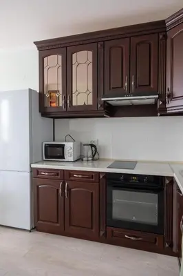 a kitchen with wooden cabinets and a white refrigerator at Апартамент в центъра на Хисаря in Hisarya