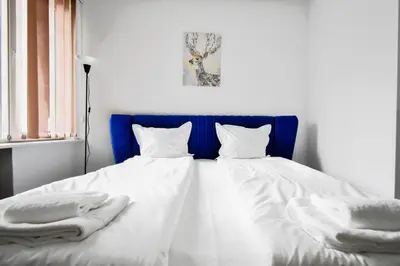 a bed with a blue headboard and white sheets and pillows at Cozy Central 1BD Apartment in Sofia