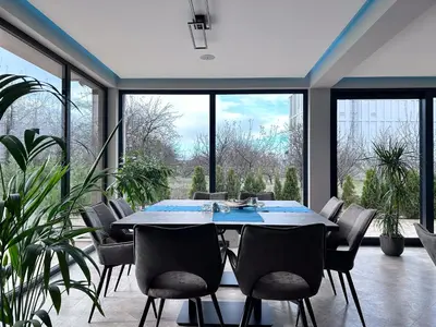 a dining room with a table and chairs and large windows at Vital Hotel in Sofia