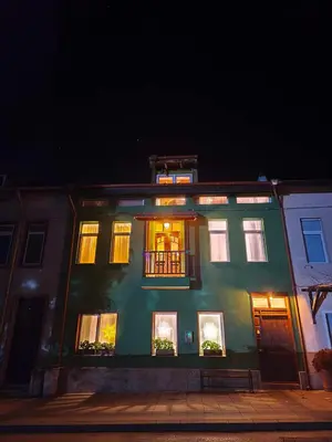 a green building with lit up windows at night at PORTALA Urban Lodge in Rila
