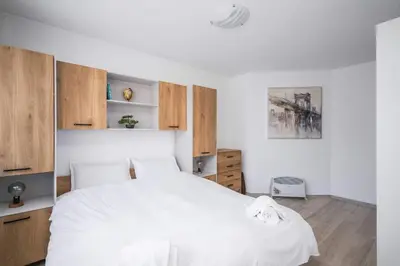 a bedroom with a white bed and wooden cabinets at Sunny & Modern 1BR Apartment in Sofia