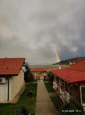 a rainbow in the sky over some houses and a sidewalk at Свети Георги in Tsigov Chark