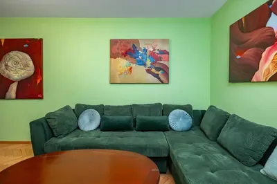 a living room with a green couch and some paintings at Life in Colours - Artistic 1BD Apartment in Sofia