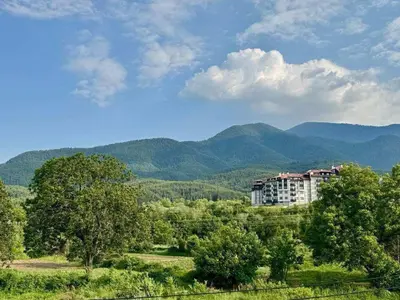 a building in a field with mountains in the background at Yeti Complex in Bansko