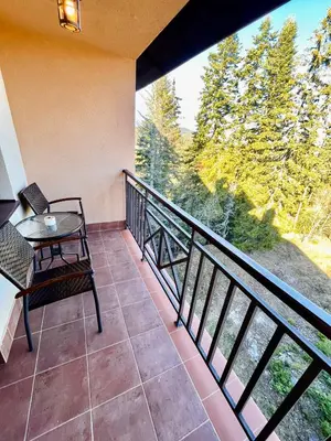 a balcony with a table and a view of trees at Pamporovo Cozy Ski-Close Nest in Pamporovo