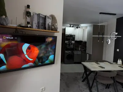 a living room with a tv on a wall and a kitchen at Elizi2 winter apartments Pamporovo in Pamporovo