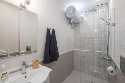 a white bathroom with a sink and a shower at Beautiful Bright and Spacious Central Apt in Sofia