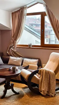 a living room with a couch and a table and a window at Cozy Stylish 2-bedroom apt near ski road, 5min to Gondola & bars in Bansko