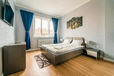 a bedroom with a bed and a window with blue curtains at Central Apartment near NDK in Sofia