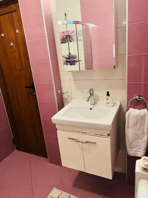 a bathroom with a sink and a mirror and pink tiles at Sofiaway Central Apartment in Sofia