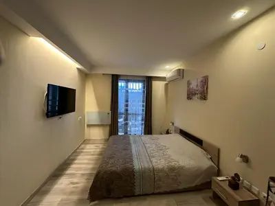 a bedroom with a bed and a tv on the wall at Aurora Apartment in Bansko