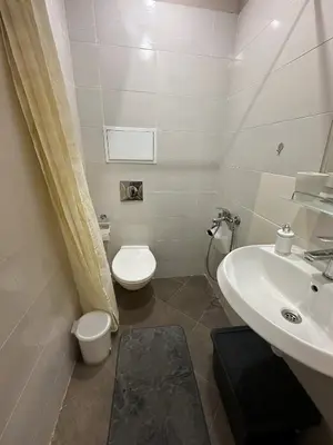 a white bathroom with a toilet and a sink at Aurora Apartment in Bansko