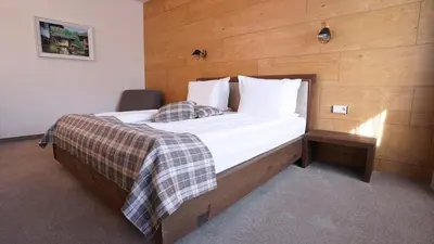 a bedroom with a large bed with a wooden wall at Комплекс Белите скали in Gaytaninovo