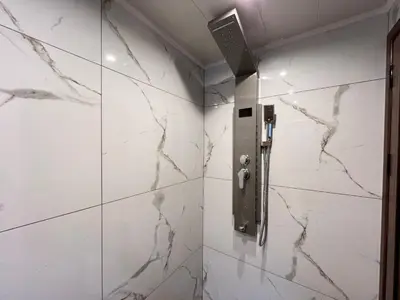 a bathroom with white marble walls and a shower stall at Стаи за гости Царвулджиеви in Koprivshtitsa