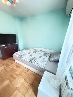 a small bedroom with a bed and a wooden floor at New cozy 3 bedroom apartment 90m2 in Sofia