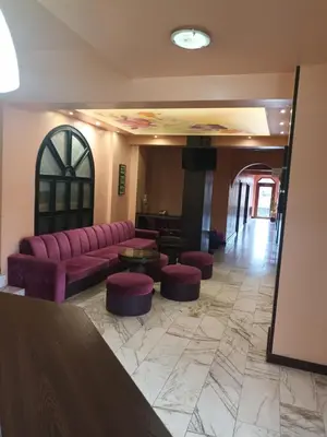 a living room with a purple couch and stools at Green Hotel Fortuna in Sapareva Banya