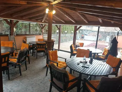 a restaurant with tables and chairs and windows at Green Hotel Fortuna in Sapareva Banya